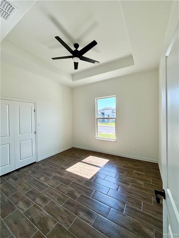 unfurnished room with ceiling fan and a raised ceiling