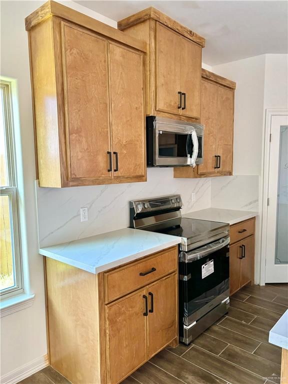 kitchen with backsplash, dark hardwood / wood-style flooring, and appliances with stainless steel finishes