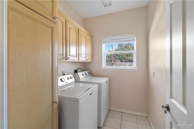 laundry room with cabinets, light tile patterned floors, and washer and dryer