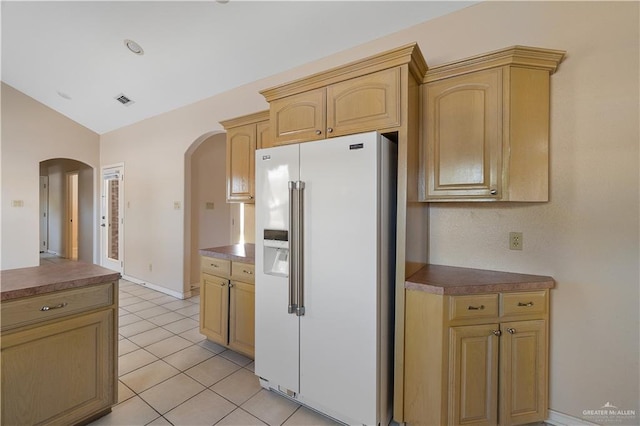 kitchen featuring high end white refrigerator, lofted ceiling, light tile patterned floors, and light brown cabinets