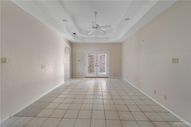 tiled spare room featuring french doors, ceiling fan, and a tray ceiling