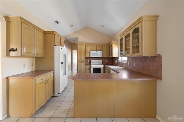 kitchen with lofted ceiling, light brown cabinets, white appliances, and kitchen peninsula