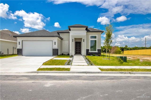 prairie-style house with stucco siding, a front yard, fence, a garage, and driveway