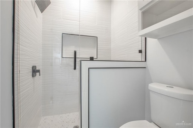 bathroom featuring a shower with shower door and toilet