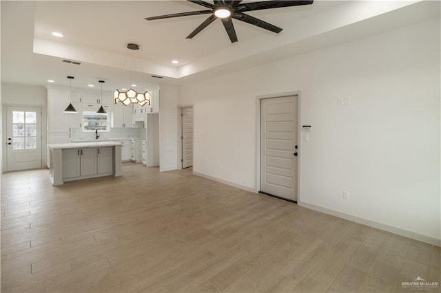 405 S 23rd St, Hidalgo, TX 78537 - unfurnished living room featuring a ceiling fan, light wood-style floors, a raised ceiling, and recessed lighting