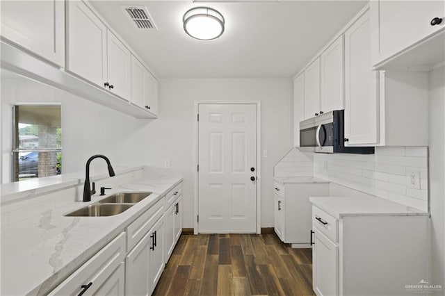 1815 W Adelita St, Weslaco, TX 78599 - kitchen featuring dark wood finished floors, light stone counters, decorative backsplash, stainless steel microwave, and white cabinetry