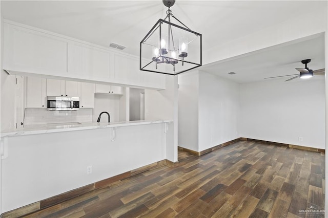 1815 W Adelita St, Weslaco, TX 78599 - kitchen with stainless steel microwave, white cabinets, backsplash, and dark wood-style floors