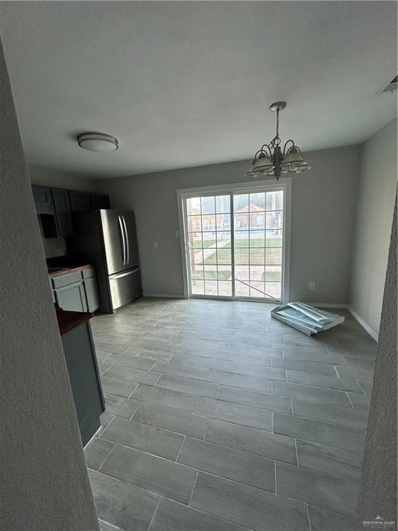 unfurnished dining area with wood-type flooring and a notable chandelier