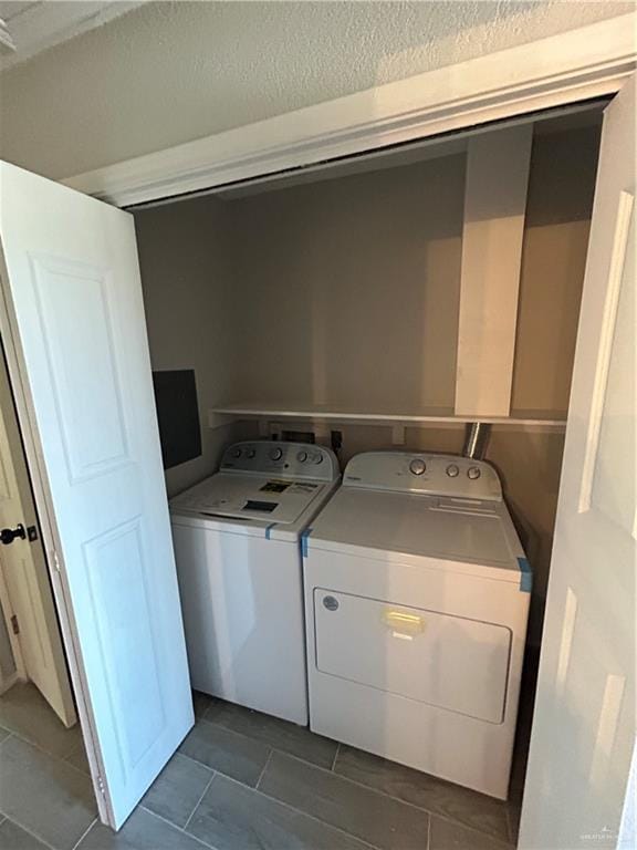 laundry area featuring washing machine and dryer and dark tile patterned flooring