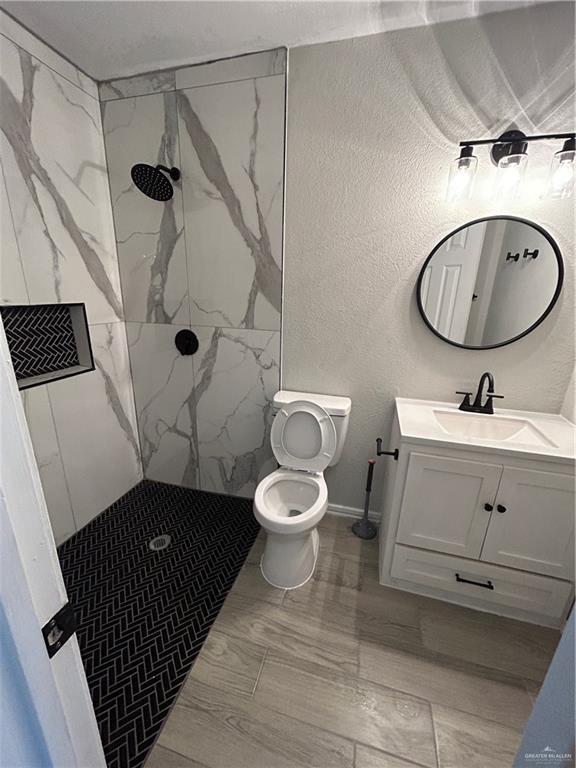 bathroom featuring vanity, toilet, and a tile shower