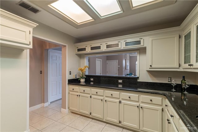 kitchen featuring glass insert cabinets, baseboards, visible vents, and light tile patterned flooring