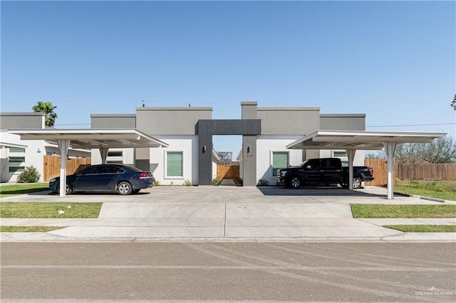 view of front of property with covered parking, stucco siding, and fence