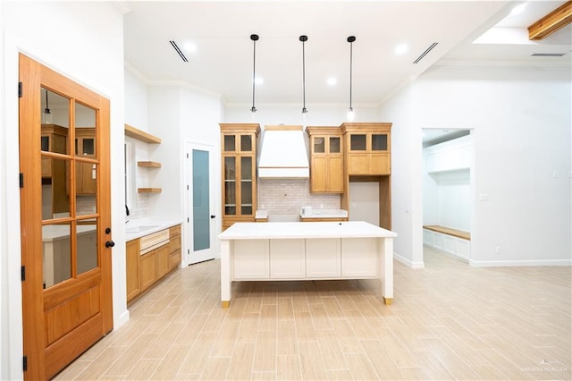 kitchen featuring tasteful backsplash, premium range hood, pendant lighting, a kitchen island, and light wood-type flooring