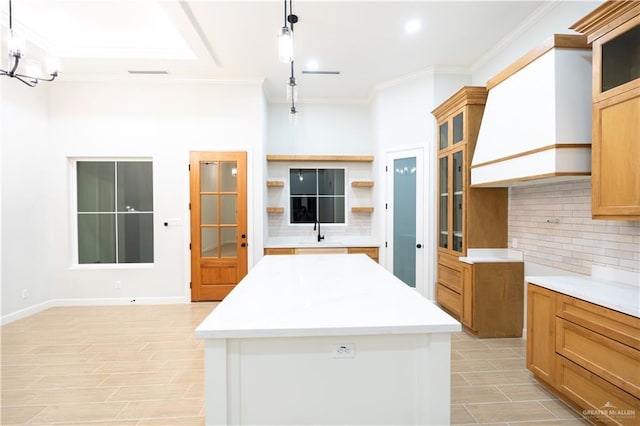 kitchen featuring light hardwood / wood-style floors, pendant lighting, decorative backsplash, a kitchen island, and ornamental molding