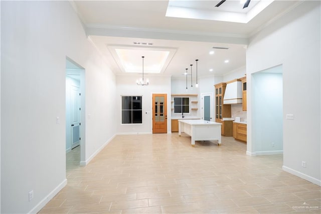 kitchen with pendant lighting, a center island, a raised ceiling, tasteful backsplash, and a chandelier