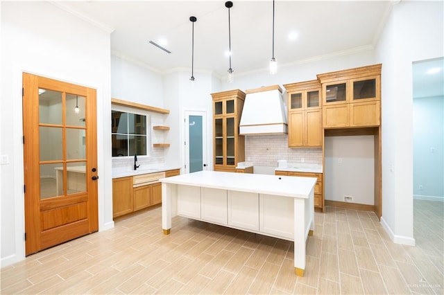 kitchen with a kitchen bar, a kitchen island, decorative light fixtures, and custom exhaust hood