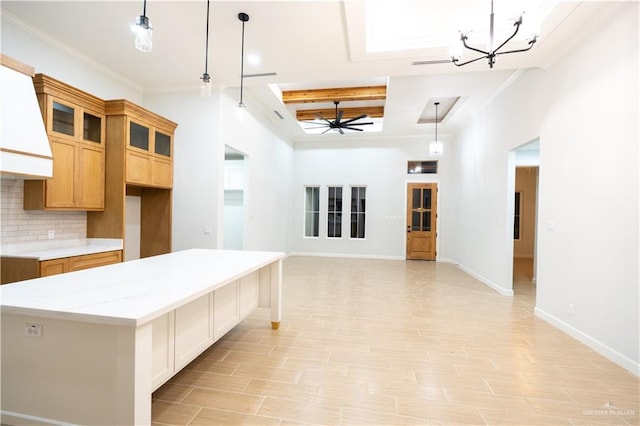 kitchen with decorative backsplash, light stone countertops, ceiling fan with notable chandelier, a center island, and hanging light fixtures