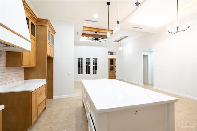 kitchen featuring decorative backsplash, light stone counters, ceiling fan with notable chandelier, pendant lighting, and a kitchen island