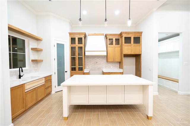 kitchen featuring sink, hanging light fixtures, tasteful backsplash, a kitchen island, and custom range hood