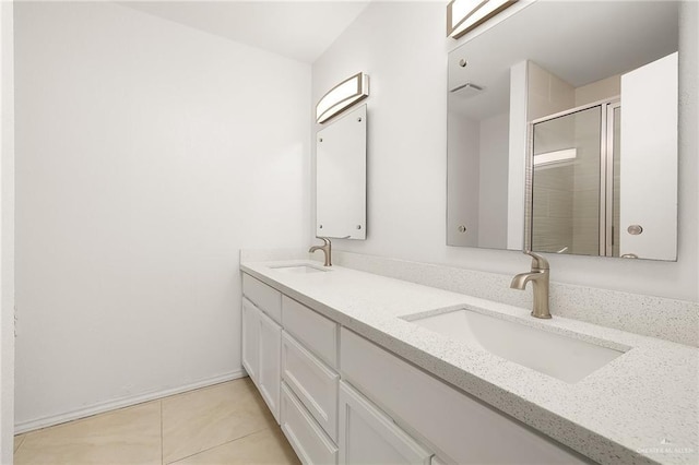 full bathroom with double vanity, a shower stall, a sink, and tile patterned floors