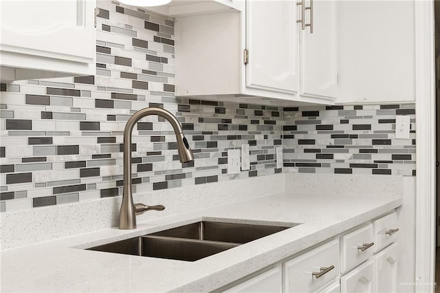 kitchen with backsplash, a sink, and white cabinetry