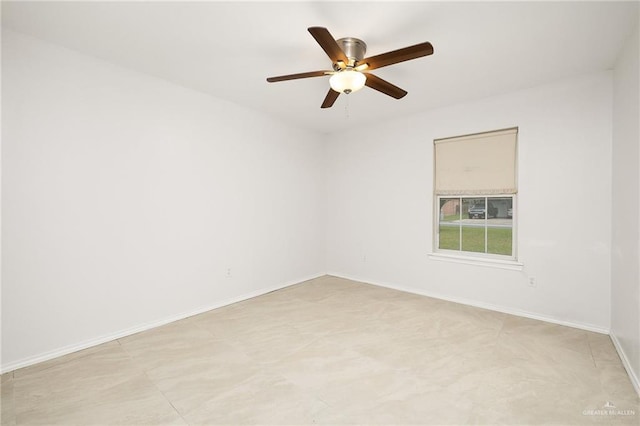 spare room featuring a ceiling fan and baseboards