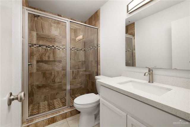 bathroom with a stall shower, vanity, toilet, and tile patterned floors