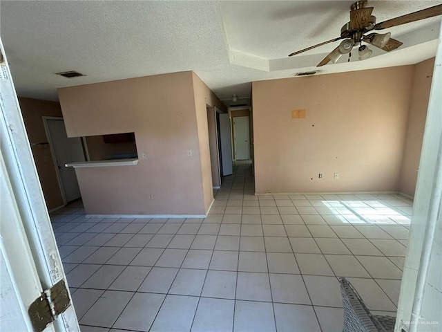 empty room with ceiling fan, light tile patterned flooring, and a textured ceiling