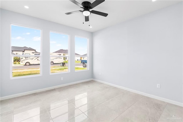 tiled empty room featuring ceiling fan and a healthy amount of sunlight