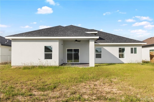 rear view of property featuring ceiling fan and a yard