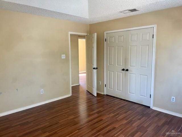 unfurnished bedroom featuring dark wood-style floors, visible vents, and a textured ceiling