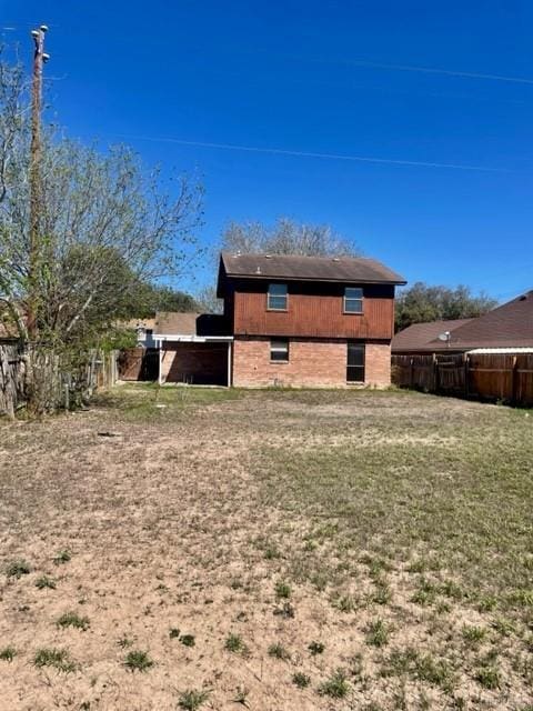 rear view of property featuring a yard and fence