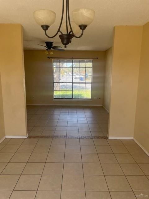 spare room featuring ceiling fan with notable chandelier, baseboards, and light tile patterned floors