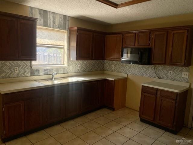 kitchen with light tile patterned floors, a textured ceiling, light countertops, and a sink