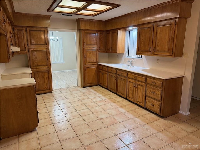 kitchen with a chandelier, a sink, visible vents, light countertops, and brown cabinetry