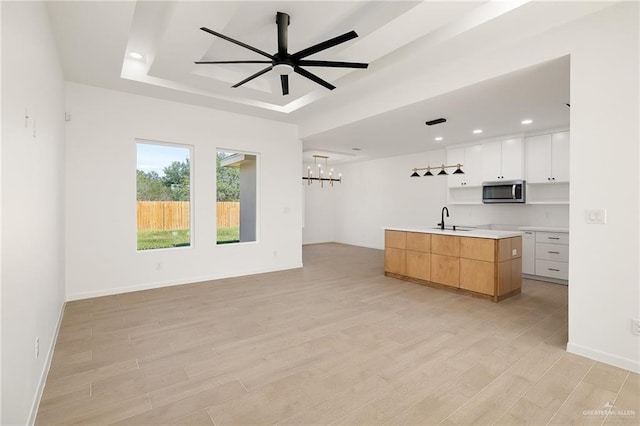 kitchen with sink, light hardwood / wood-style flooring, white cabinetry, and an island with sink