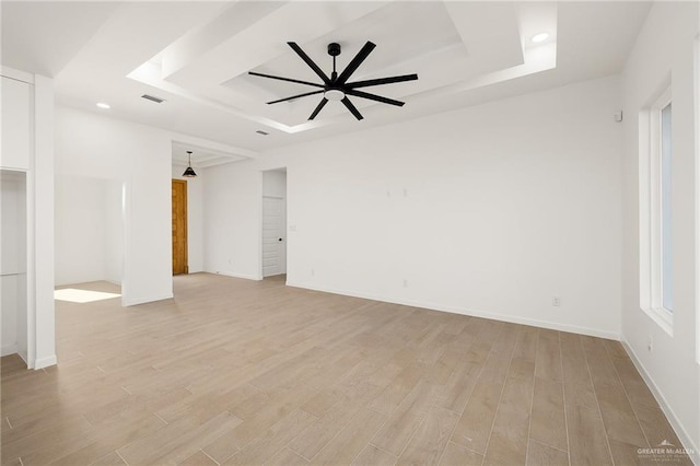 unfurnished room with a tray ceiling, ceiling fan, and light hardwood / wood-style floors