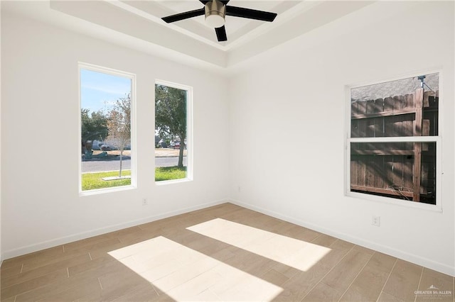 empty room featuring ceiling fan, a raised ceiling, and light hardwood / wood-style flooring