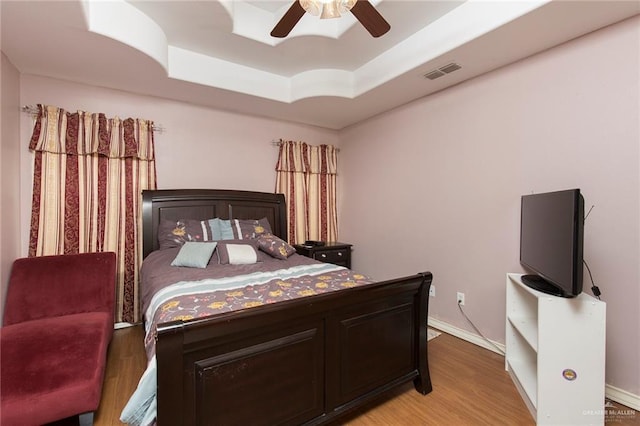 bedroom featuring a tray ceiling, light hardwood / wood-style floors, and ceiling fan