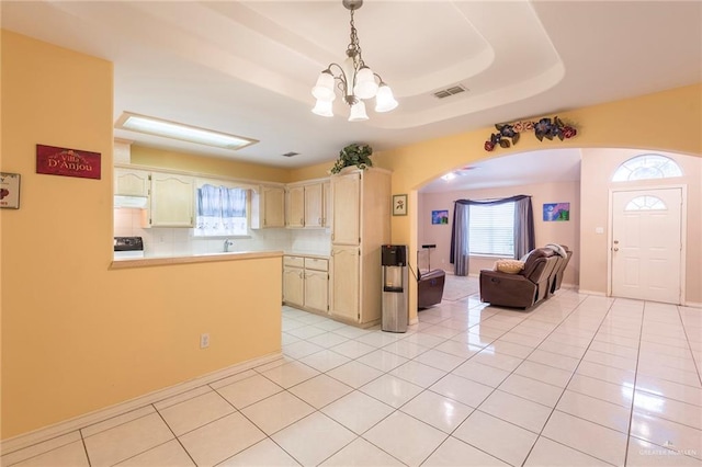 kitchen featuring tasteful backsplash, hanging light fixtures, light tile patterned floors, a tray ceiling, and kitchen peninsula