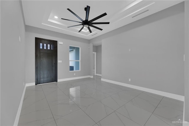 empty room featuring ceiling fan and a raised ceiling