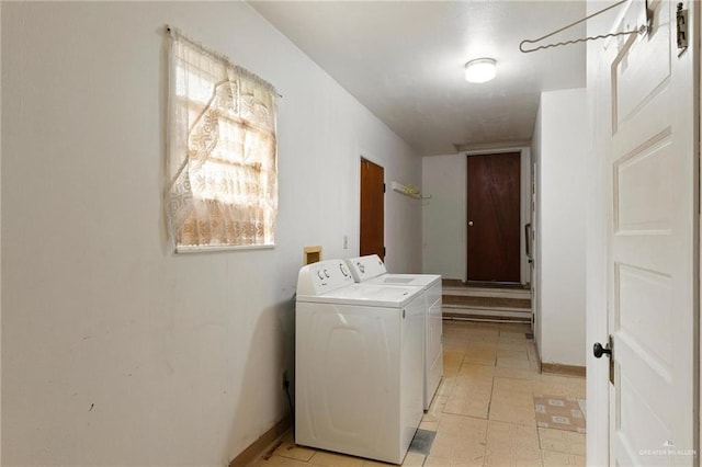 washroom featuring washing machine and dryer, baseboards, and laundry area