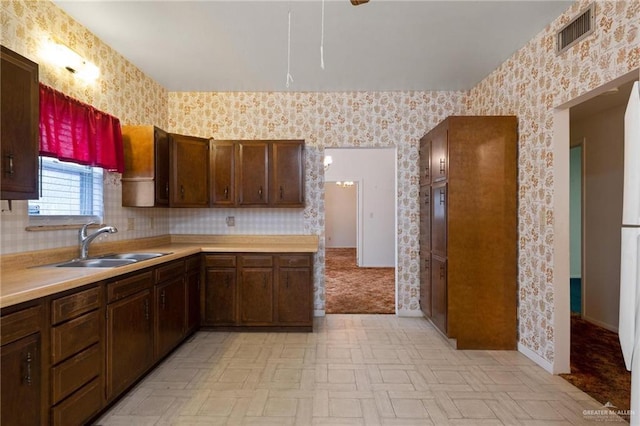 kitchen featuring a sink, visible vents, baseboards, wallpapered walls, and light countertops