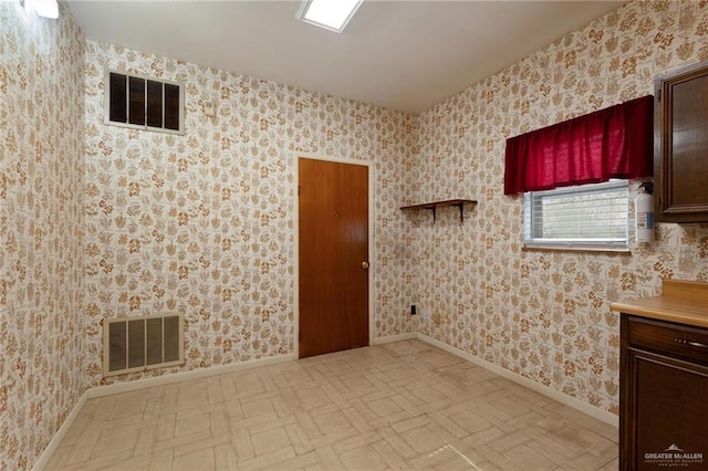 empty room with baseboards, visible vents, and wallpapered walls