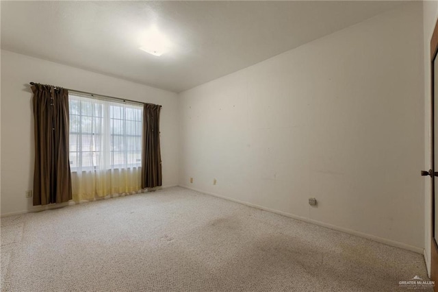 spare room with baseboards and carpet floors