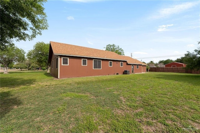rear view of house with fence, a yard, and cooling unit