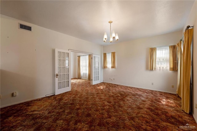 unfurnished room with baseboards, a notable chandelier, carpet flooring, and visible vents