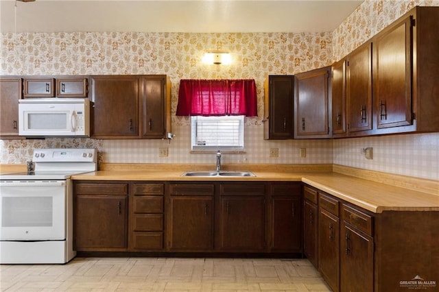 kitchen featuring a sink, wallpapered walls, white appliances, light floors, and light countertops