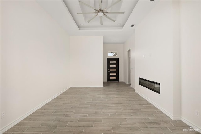 unfurnished living room with a raised ceiling and ceiling fan