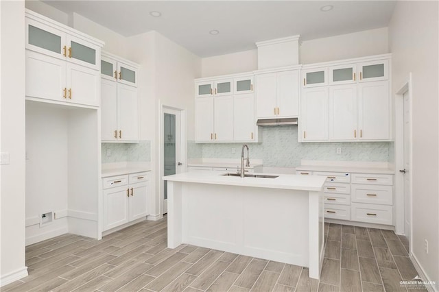 kitchen featuring light wood-type flooring, white cabinetry, sink, and an island with sink